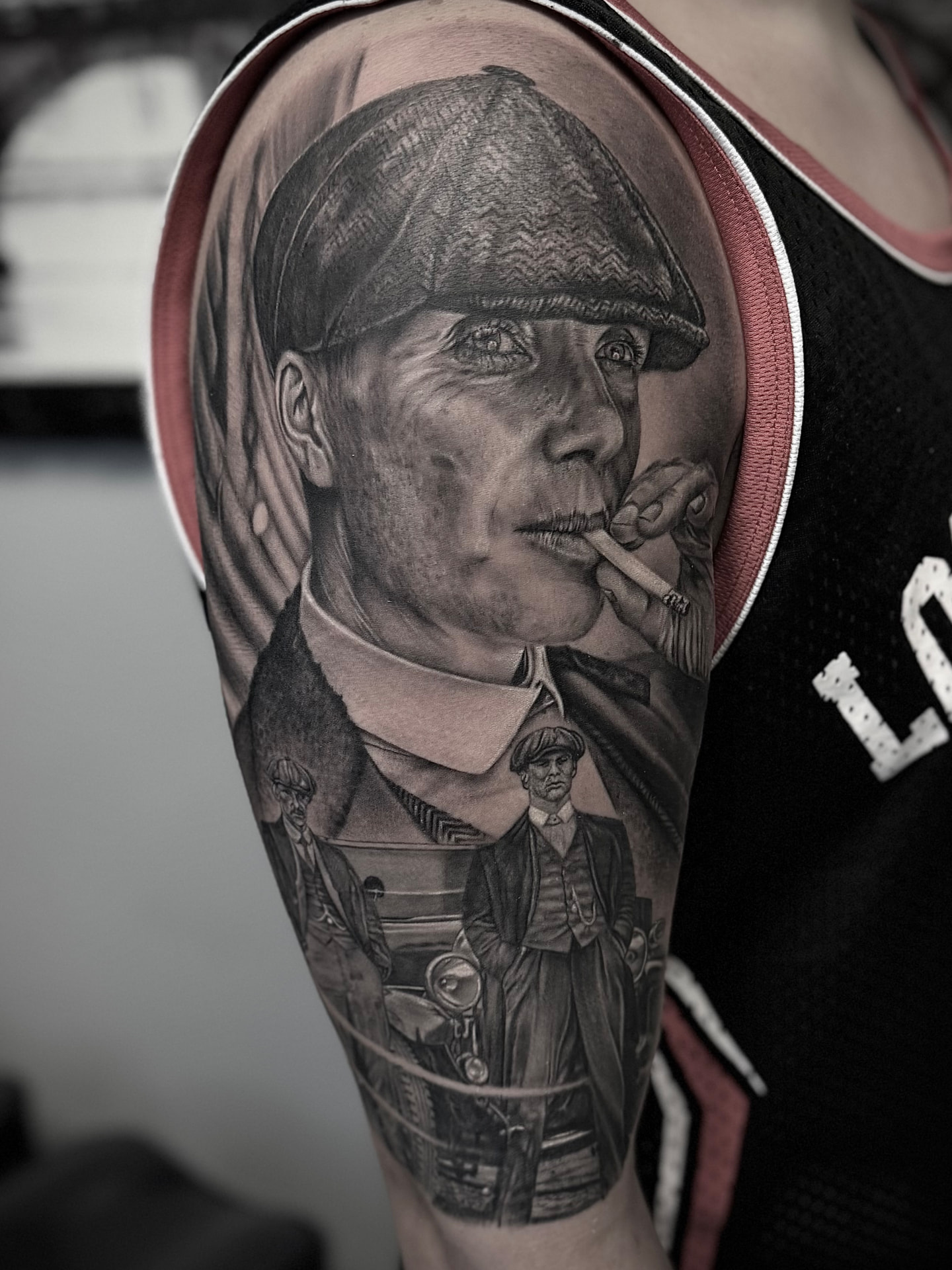 Tatuaggio realistico in bianco e nero su spalla e braccio con ritratto e scena d'epoca